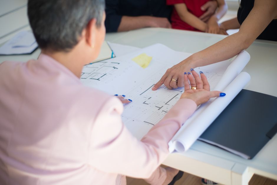 Two well-dressed professionals collaborating over architectural blueprints in a bright, modern office, symbolizing a strat...