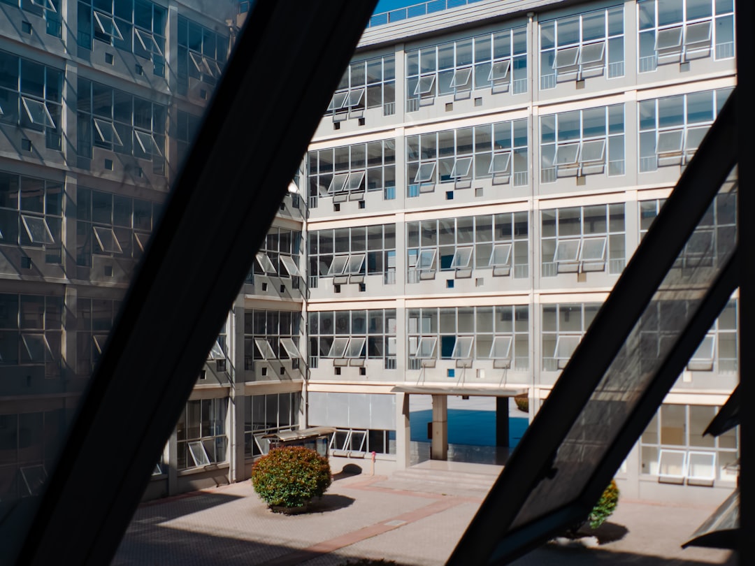 A well-dressed professional stands in a modern, minimalist office, looking thoughtfully through a large window at a dynamic city skyline, representing strategic financial planning.