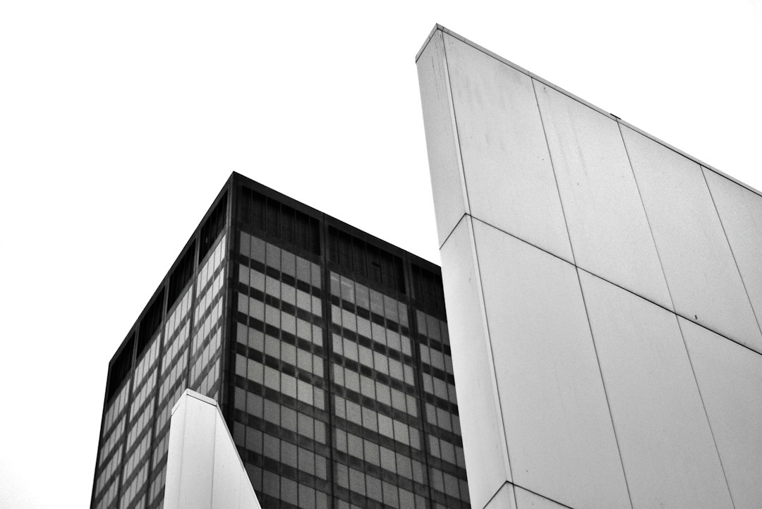 Striking architectural contrast between a modern glass skyscraper and an older brick building, symbolizing the evolution o...